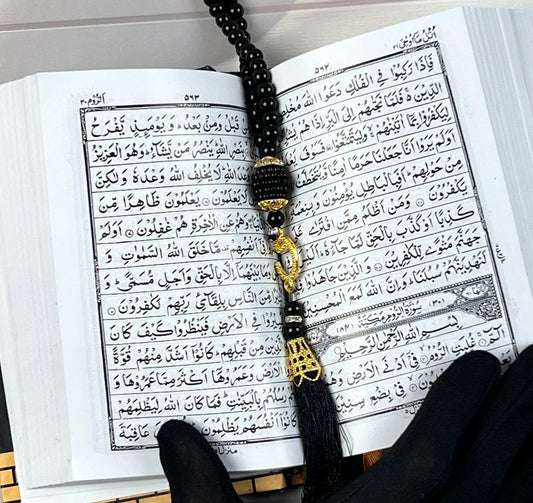 Small Arabic Quran with Kaaba-inspired golden design and black tasbih.