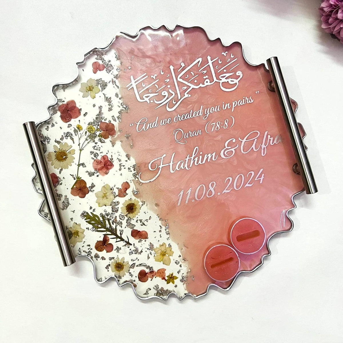 Floral resin wedding ring tray with silver accents and decorative base.