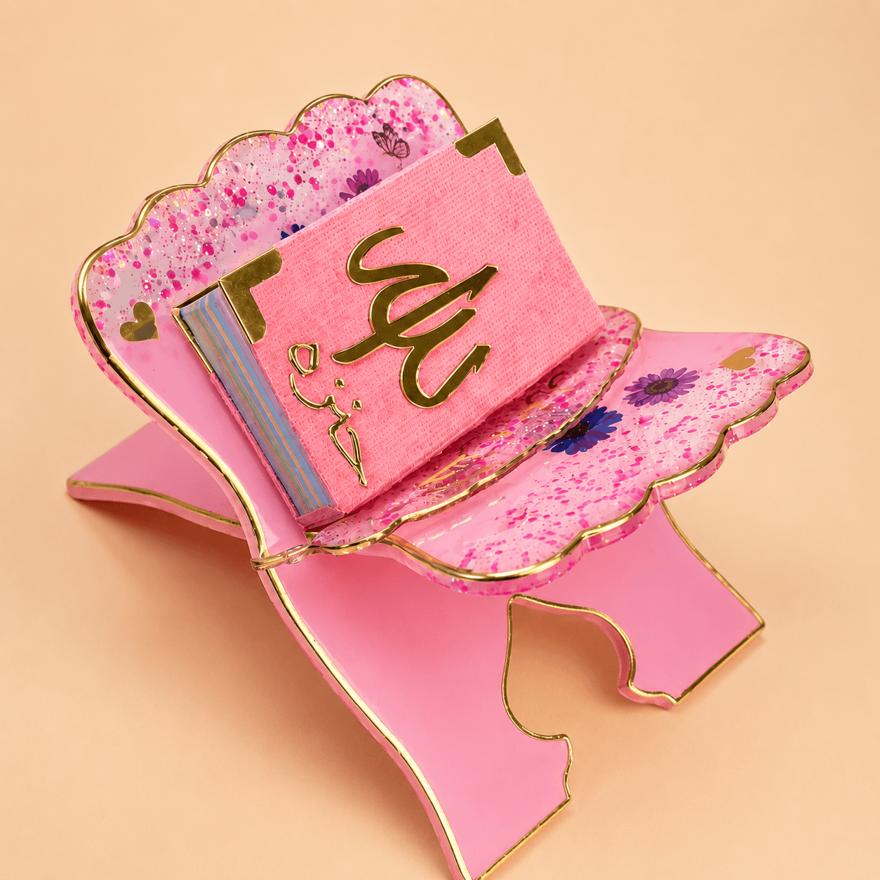 Pink decorative box with gold accents and floral patterns on a beige background