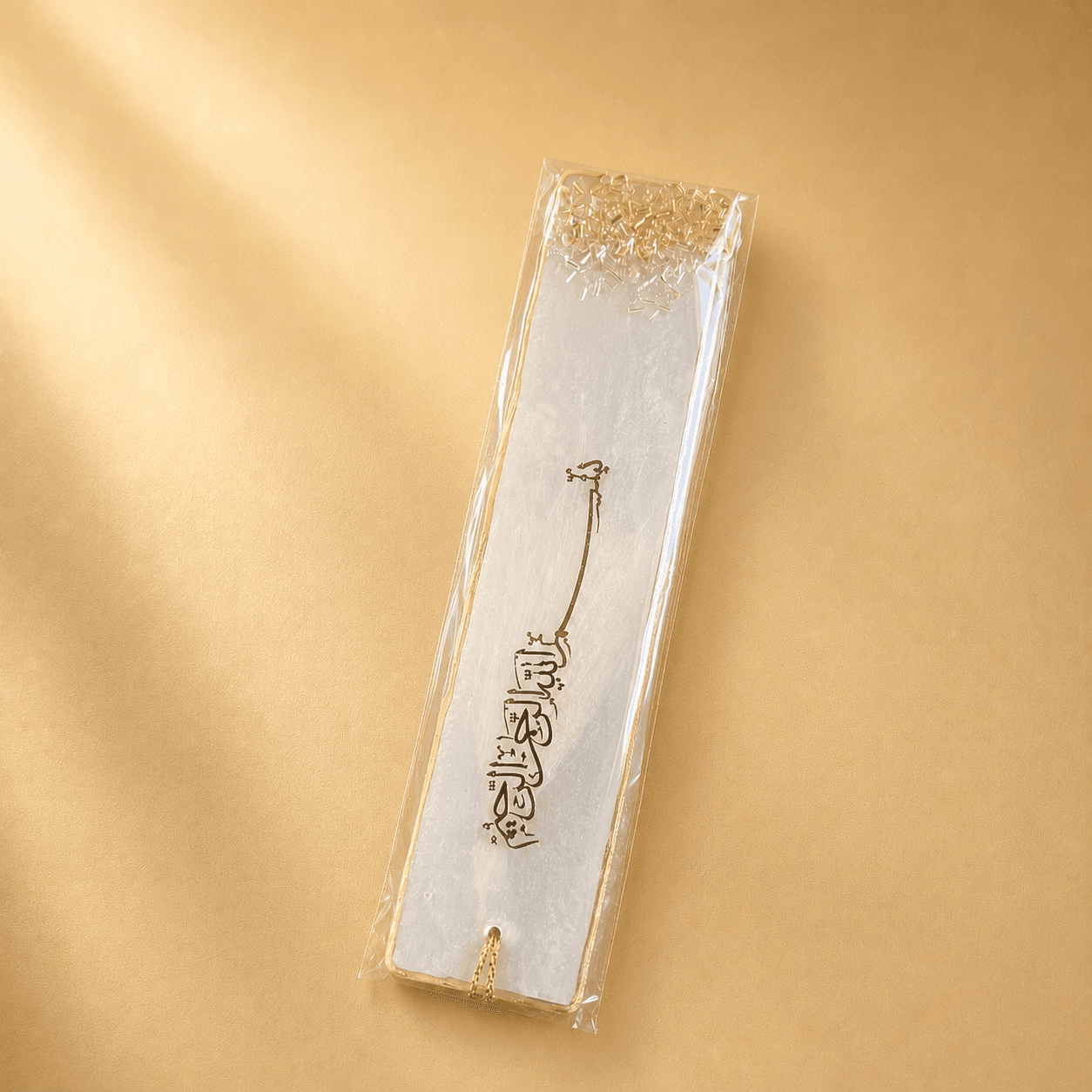 Silver bookmark with gold accents in clear packaging on a gold background