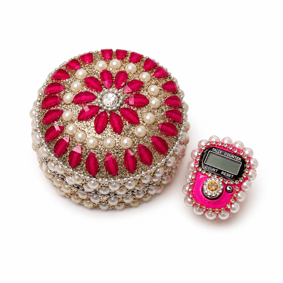 Decorative round object with red stones and pearls next to a digital device with pink casing and pearl accents on a white background.