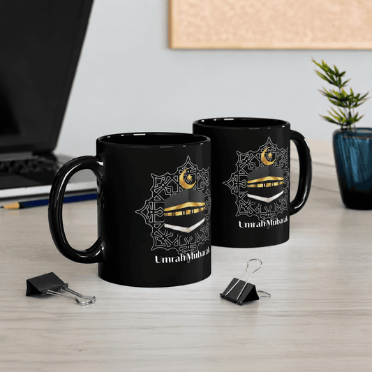 Two black mugs with gold and white designs on a desk with office supplies.