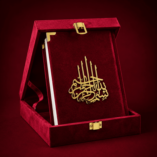 A gold-tone Islamic calligraphy plaque presented inside an open red velvet book-shaped gift box with gold corner accents and clasps, set against a dark red background.