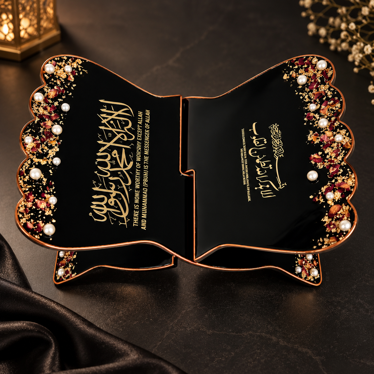 A premium black wooden Quran rehal with intricate gold detailing, pearl embellishments, and dried floral accents, placed on a dark elegant surface with warm ambient lighting and black satin fabric.