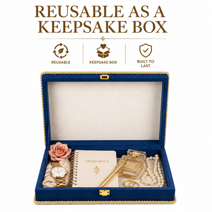 An open blue keepsake box with gold trim, shown on a white background with marketing text above. The box contains a watch, rose, notebook, perfume bottle, necklace, rings, and a pearl strand.