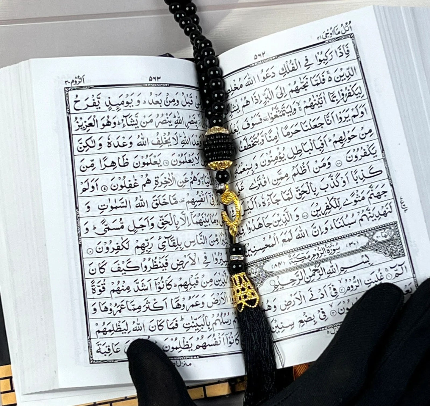 Small Arabic Quran with Kaaba-inspired golden design and black tasbih.