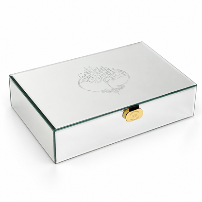 A rectangular mirrored glass keepsake box with a gold clasp and an engraved Arabic calligraphy design on the lid, shown on a white background.