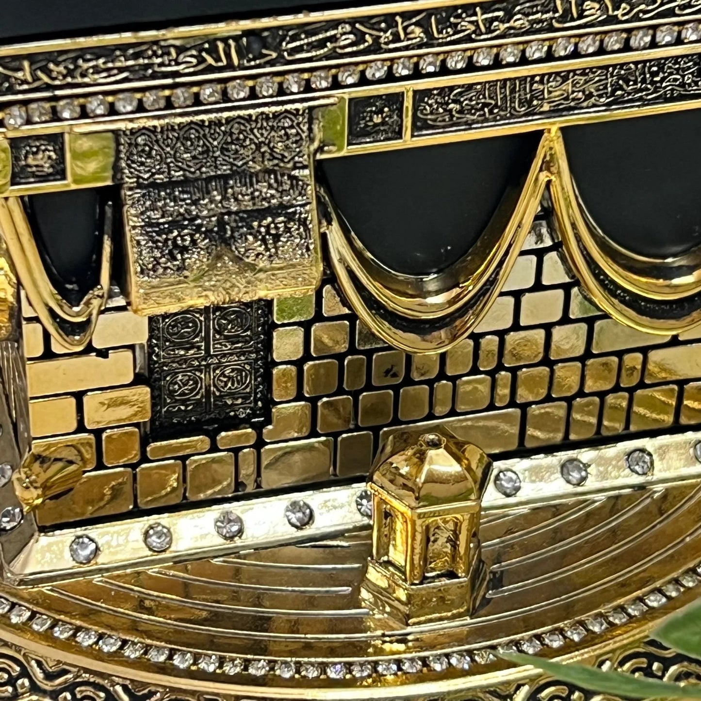 zoom in of Golden Kaaba replica with Arabic calligraphy and luxury detailing.