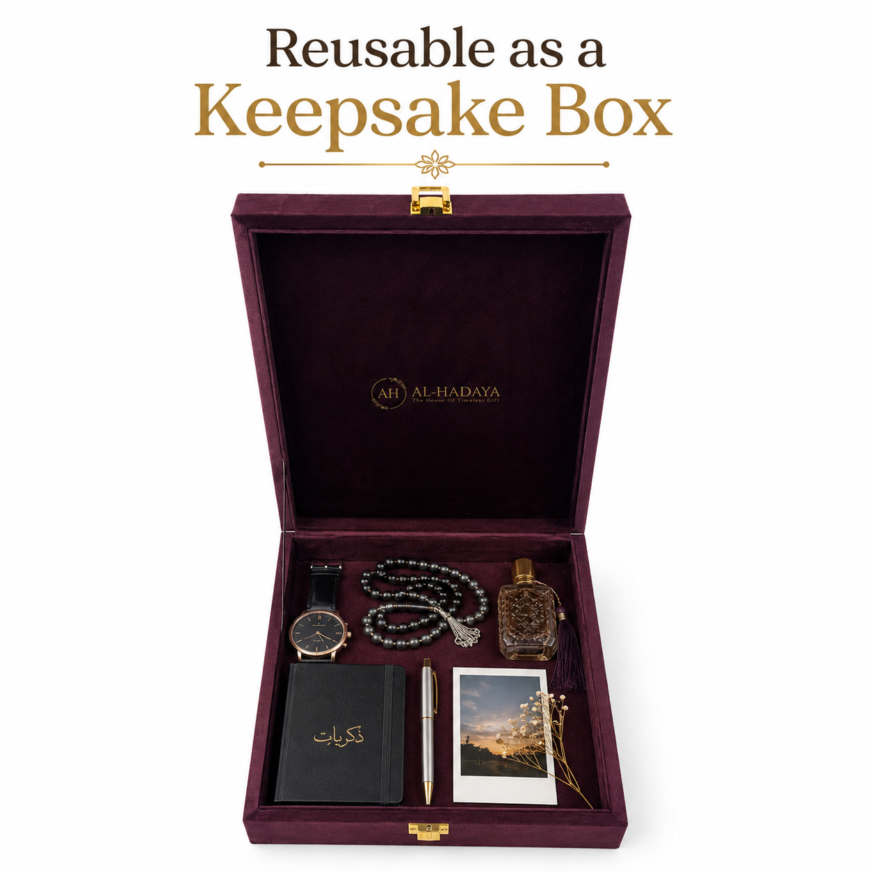 An open dark burgundy keepsake box with gold hardware, branded AL-HADAYA, shown on a white background with the text 'Reusable as a Keepsake Box' above it. Inside are several gift items arranged neatly: a black journal with gold lettering, a silver pen, a watch, a beaded necklace, a perfume bottle, a small photo card, and a gold-toned keepsake pin.