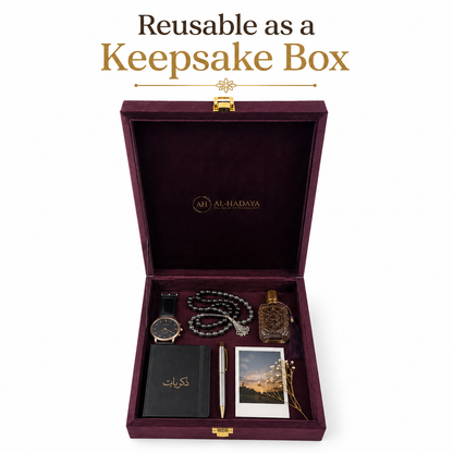 An open dark burgundy keepsake box with gold hardware, branded AL-HADAYA, shown on a white background with the text 'Reusable as a Keepsake Box' above it. Inside are several gift items arranged neatly: a black journal with gold lettering, a silver pen, a watch, a beaded necklace, a perfume bottle, a small photo card, and a gold-toned keepsake pin.