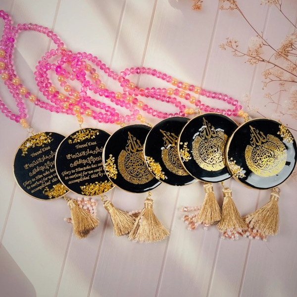 Islamic car hanger with Travel Dua in gold calligraphy on black resin pendant, decorated with pink and peach beads, gold tassel, and pearl accents.