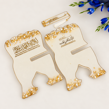 Two decorative wooden Eid Mubarak cards shaped like an elephant, decorated with gold foil, white faux pearls, and Arabic calligraphy, displayed on a white surface with blue flowers in the corner.
