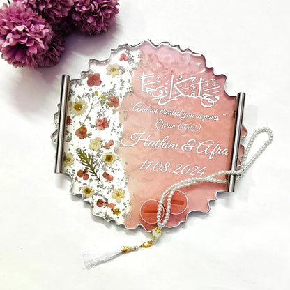 Floral resin wedding ring tray with silver accents and decorative base.