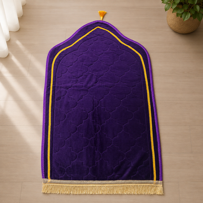A purple prayer rug with a gold border and tassel, laid flat on a light wood floor.