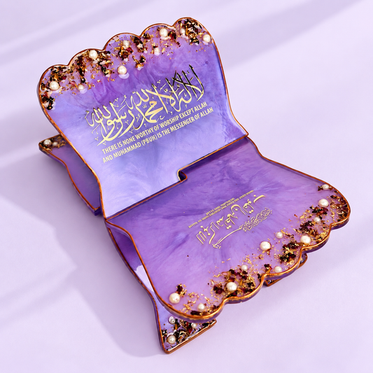 Premium purple resin Rehal with elegant gold detailing, pearl embellishments, ornate Arabic calligraphy, and a scalloped design, presented on a soft lavender background.