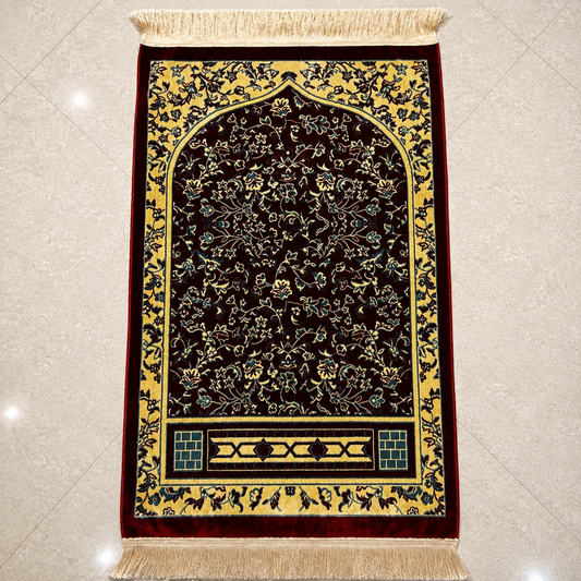 A rectangular Islamic prayer rug with an ornate arch design, featuring a dark brown center, a golden-yellow border, and intricate floral patterns in green, blue, and gold, finished with a beige fringed top and bottom.
