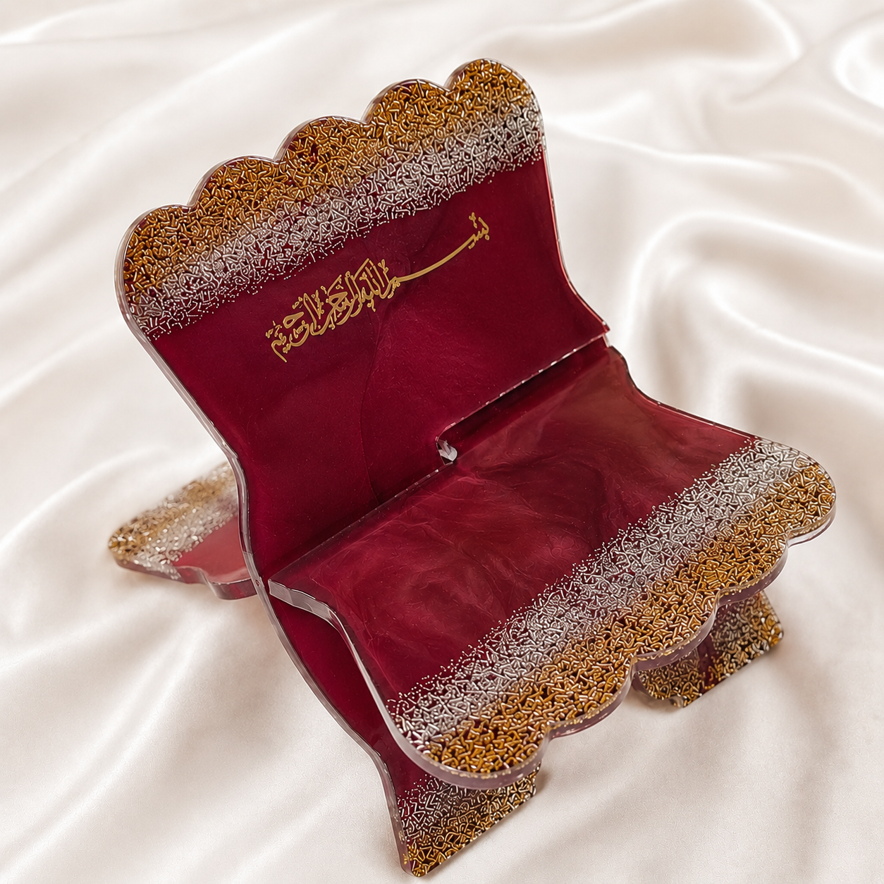 Decorative red and gold box with intricate patterns on a white fabric background