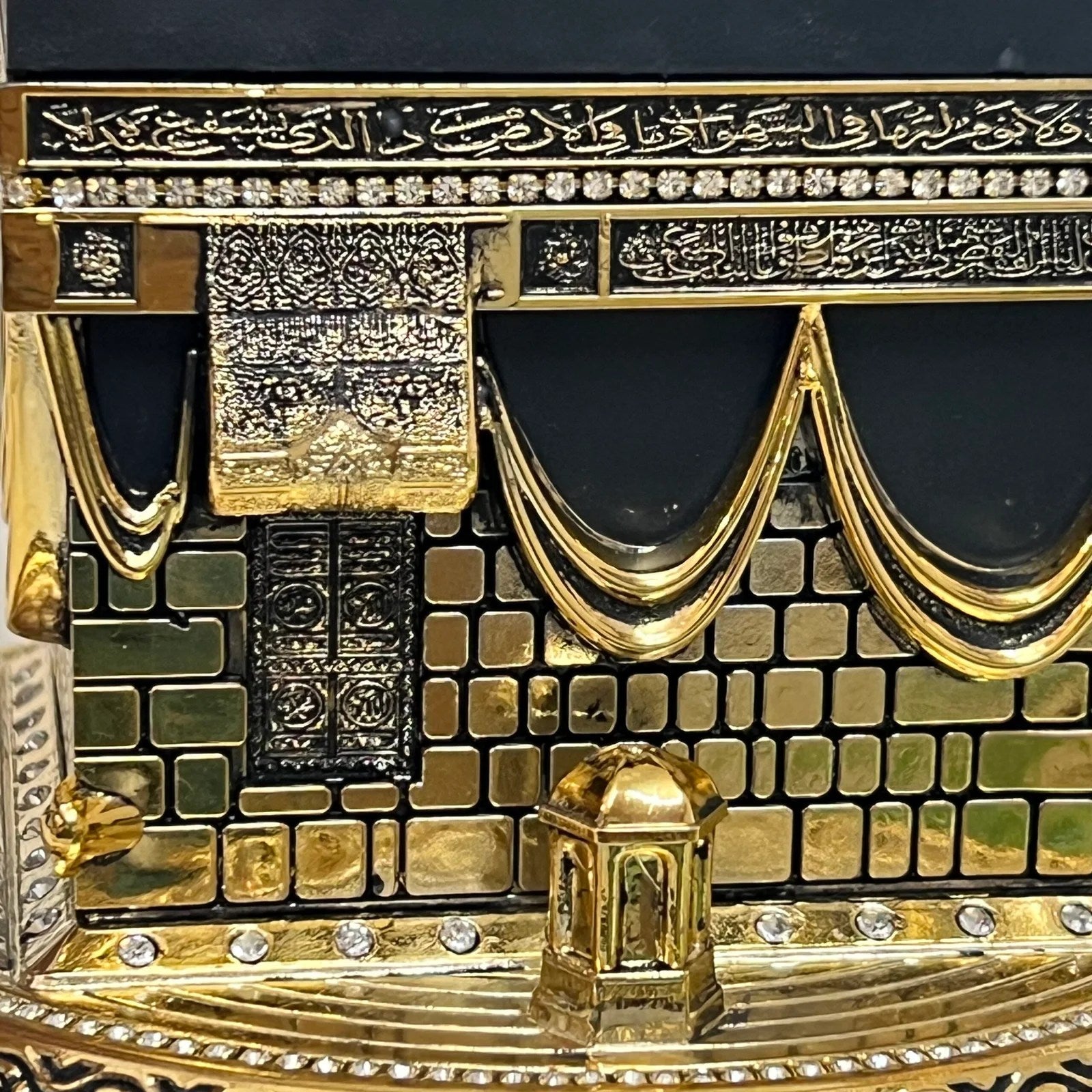 zoom in of Unique Islamic table decoration featuring Kaaba replica in gold and black.