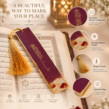 A decorative book bookmark with a gold tassel, featuring a deep burgundy-red center with gold Arabic calligraphy and dried red flower accents, displayed on a round beige marble coaster.