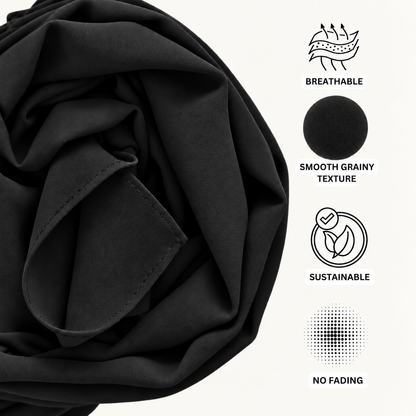 Black fabric shown in a close-up with printed feature icons and text on the right reading 'BREATHABLE', 'SMOOTH GRAINY TEXTURE', 'SUSTAINABLE', and 'NO FADING'.