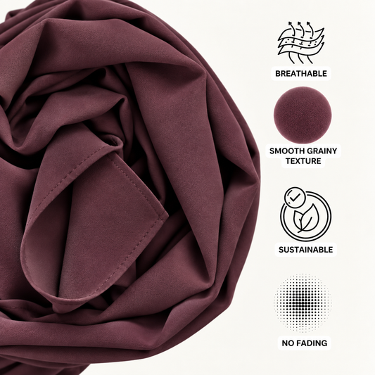 A close-up of draped burgundy fabric on a white background with feature icons and text reading Breathable, Smooth Grainy Texture, Sustainable, and No Fading.