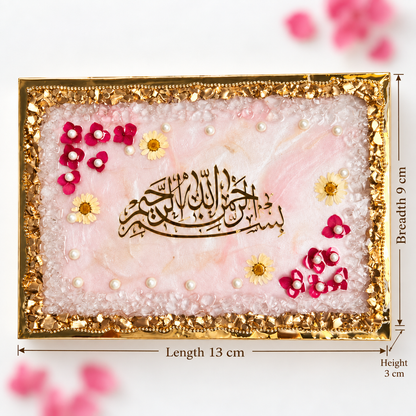 A rectangular decorative plaque or tray with Arabic calligraphy in the center, surrounded by a gold border and embellished with pink and yellow flower accents and small pearl-like beads. Measurement labels indicate a length of 13 cm, breadth of 9 cm, and height of 3 cm.