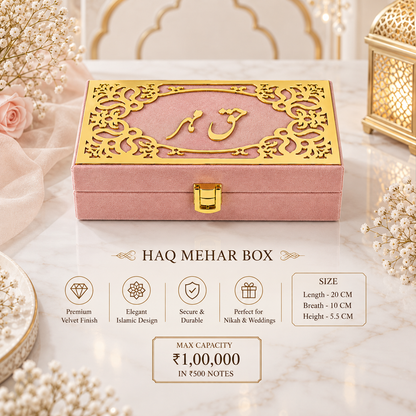A pink velvet HAQ MEHAR BOX with an ornate gold laser-cut lid featuring Arabic calligraphy, displayed on a marble surface with decorative floral props. The image includes feature callouts and size information below the product.