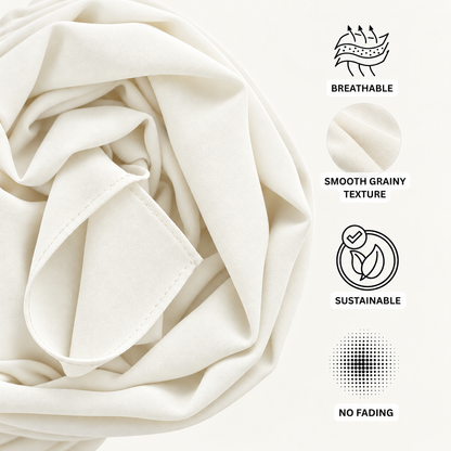 Close-up of cream-colored fabric with a smooth grainy texture, shown with black line icons and text highlighting features: breathable, smooth grainy texture, sustainable, and no fading.