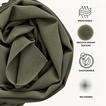 An olive green fabric product, likely a sheet or duvet cover, shown in a close-up with feature callouts on the right. The text and icons highlight its breathable, smooth grainy texture, sustainable quality, and no-fading properties.