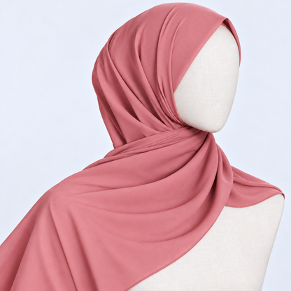 A dusty rose pink hijab draped elegantly on a white mannequin head and shoulders against a light blue background.
