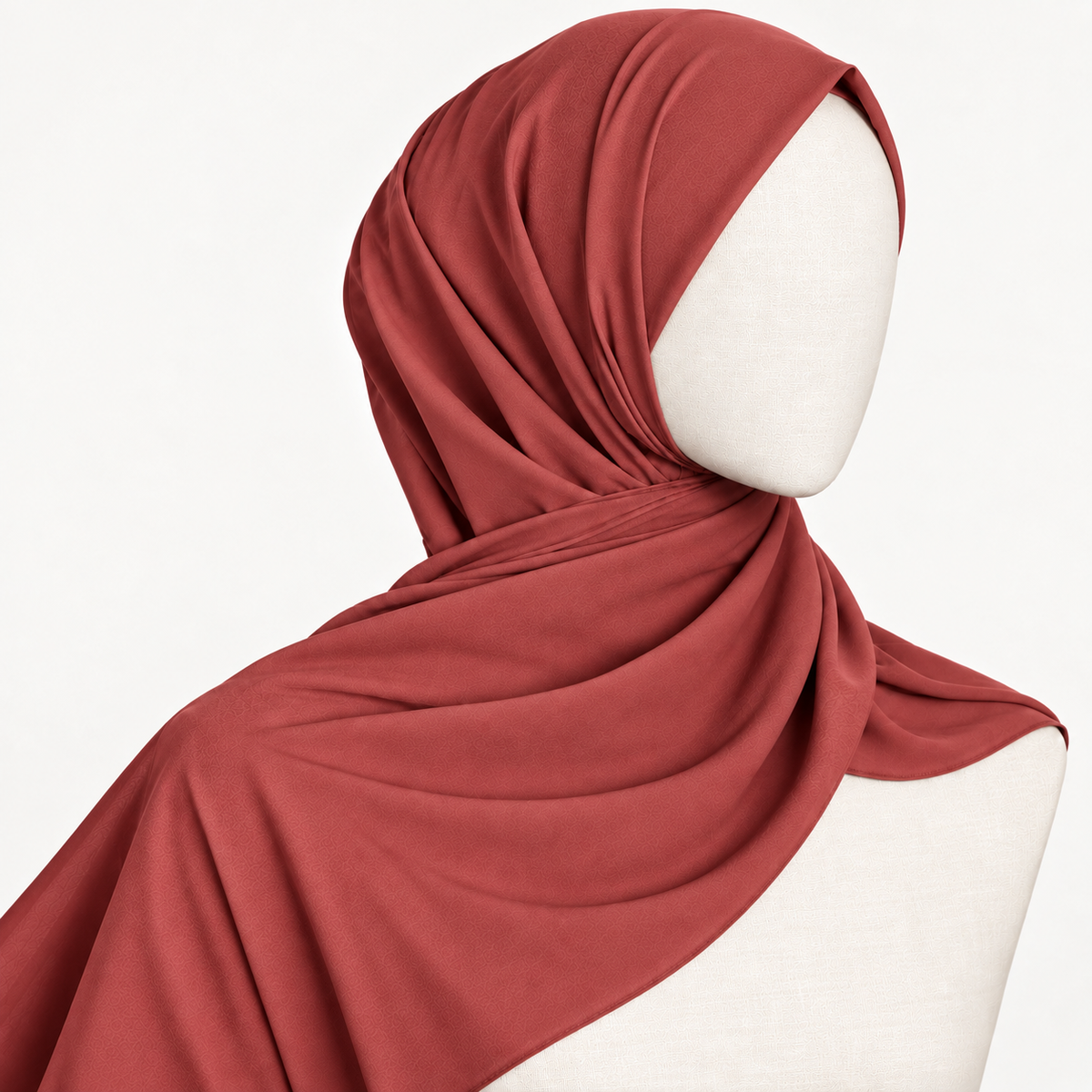 A draped terracotta red hijab scarf styled on a white mannequin head and shoulders against a clean white background.
